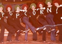 Acht Frauen machen Jazz-Dance mit dem Schriftzug POPCORN auf den T-Shirts